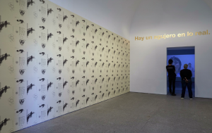 Dora García: arte en el aire Vista de una sala de la exposición Segunda vez de Dora García. Junto al muro empapelado con el lacaniano papel pintado se sitúa una obra de la serie Golden Sentences. Al fondo, la película "La lección respiratoria".