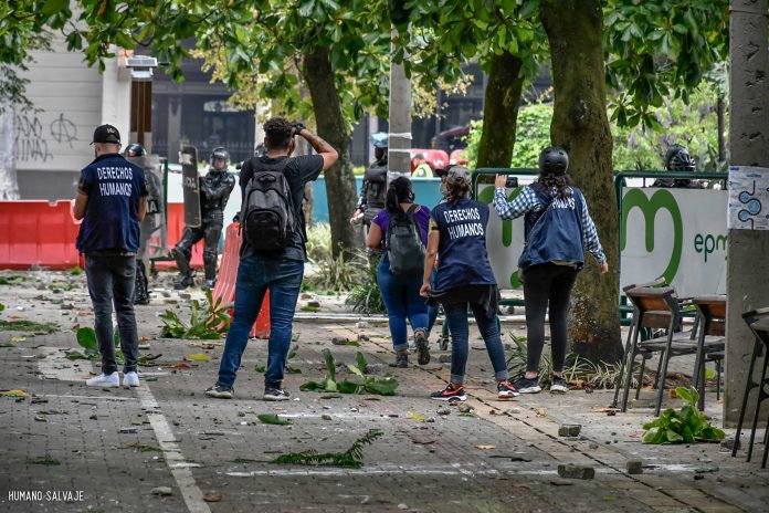 Paro Colombia 2021 Defensores de Derechos Humanos intentan dialogar con policías del ESMAD (escuadrón móvil antidisturbios) en la avenida San Juan, frente al Centro Administrativo Departamental La Alpujarra, en Medellín, Colombia, para que garanticen el derecho a la protesta, se respeten las libertades recogidas en la Constitución en los enfrentamientos del Paro Nacional Colombiano iniciado el 28 de abril. Foto de Humano Salvaje distribuida por Flickr bajo licencia Attribution-ShareAlike 2.0 Generic (CC BY-SA 2.0).